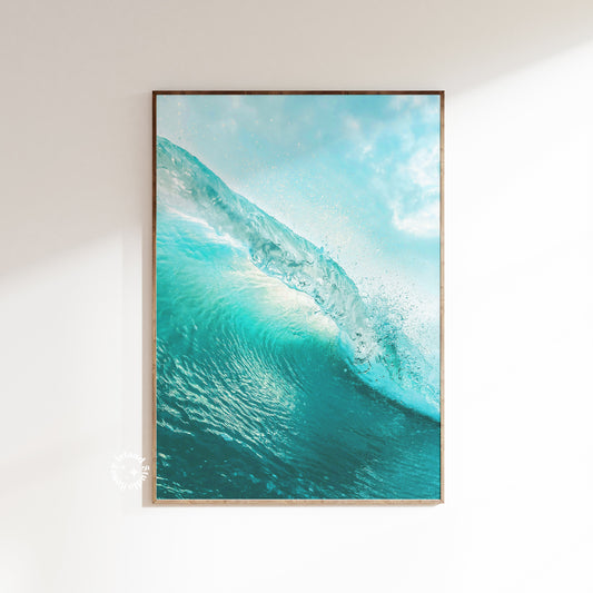 A framed poster featuring a vibrant image of a wave cresting in blue and turquoise colors, designed for beach house decor.