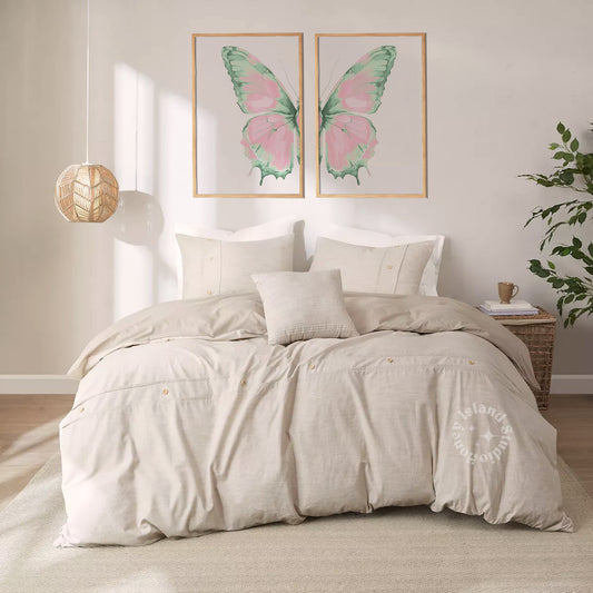 Neatly made bed with beige bedding in a room with butterfly artwork on the wall.