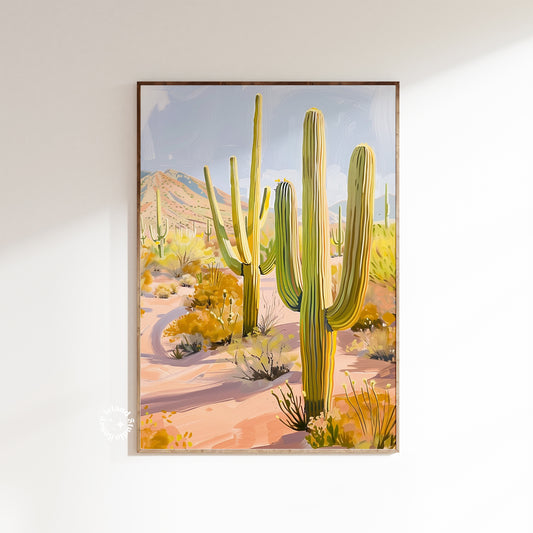 Framed artwork of a desert scene with cacti on a white wall.