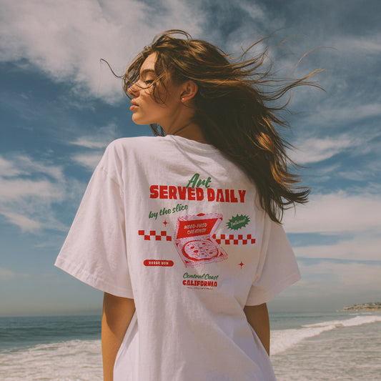 a person wearing a white t-shirt with a graphic design on the beach