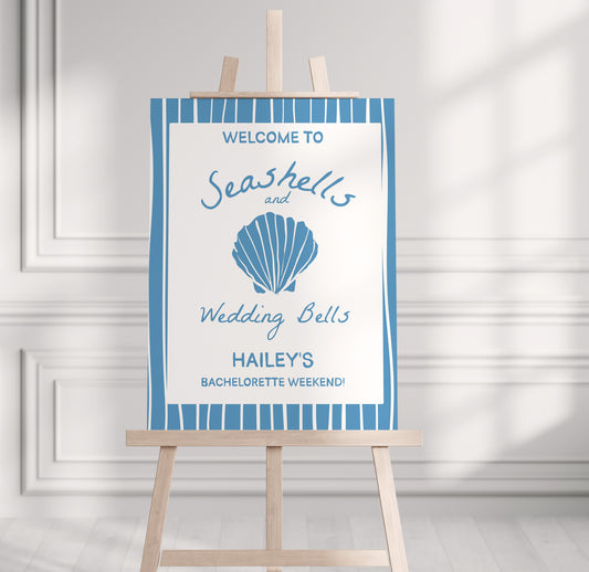 Decorative sign with a shell design on an easel against a white wall.