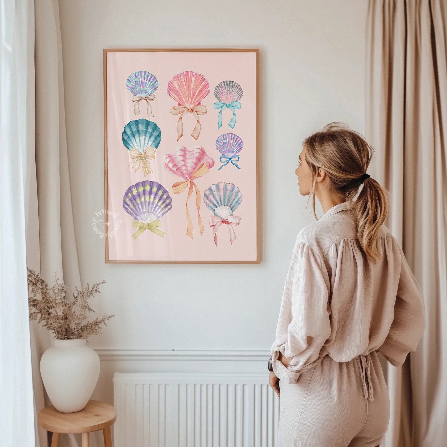 Woman standing in a room looking at a framed artwork of colorful seashells on a wall.
