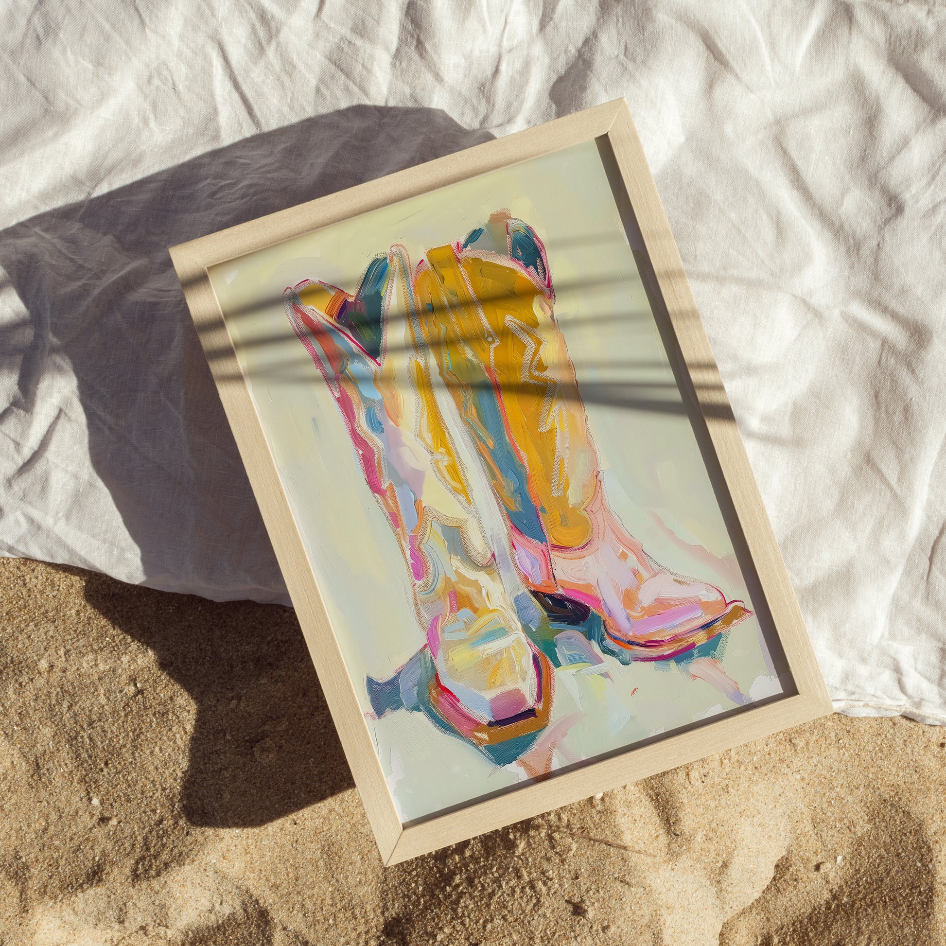 Colorful abstract art print of a westenr boots on a sandy surface with a white blanket.