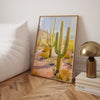 Framed artwork of a desert scene with cacti in a beedroom floor