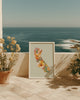 Framed floral artwork on a patio with ocean view