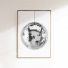 A disco ball poster with a white and silver design, depicting a reflective mirror ball, framed and displayed on a wall.