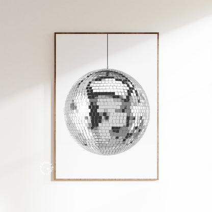 A disco ball poster with a white and silver design, depicting a reflective mirror ball, framed and displayed on a wall.