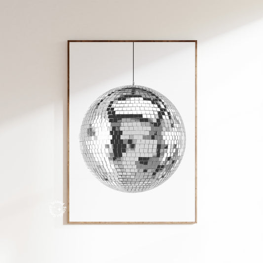 A disco ball poster with a white and silver design, depicting a reflective mirror ball, framed and displayed on a wall.