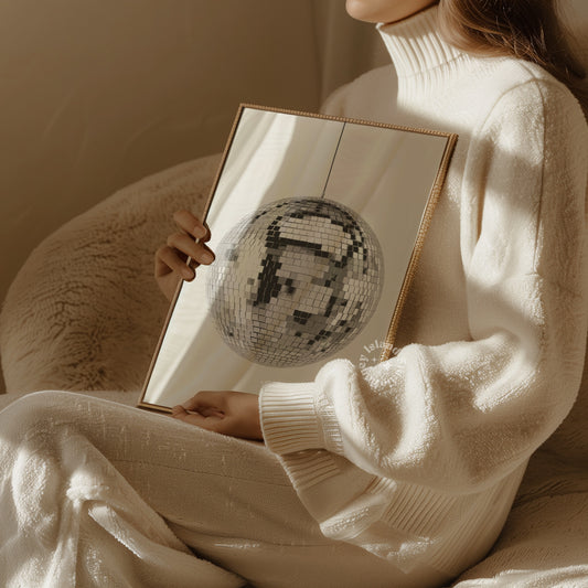 womn holding a framed poster with a silver disco ball printed.