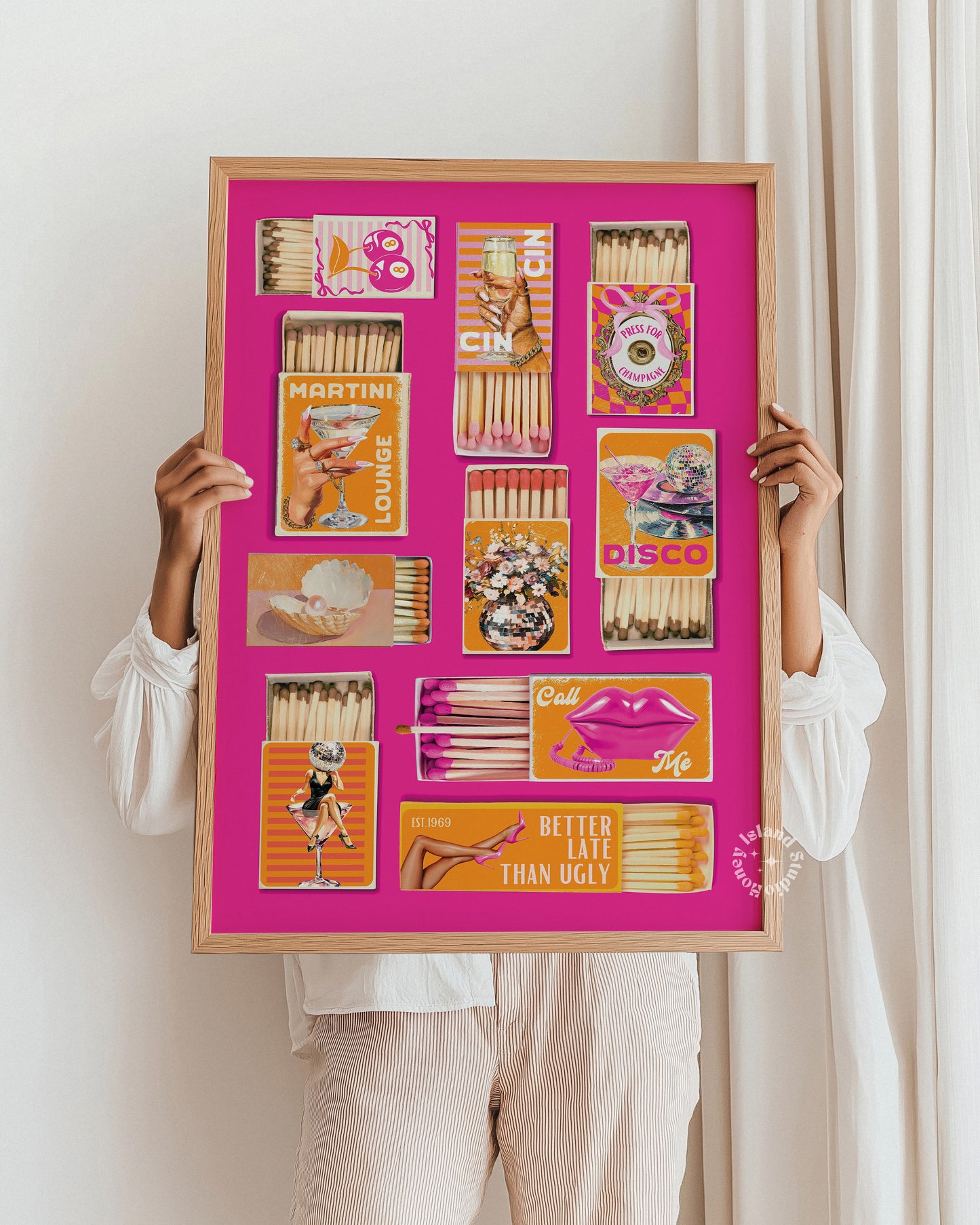 Person holding a framed artwork with matchbox art on a pink background