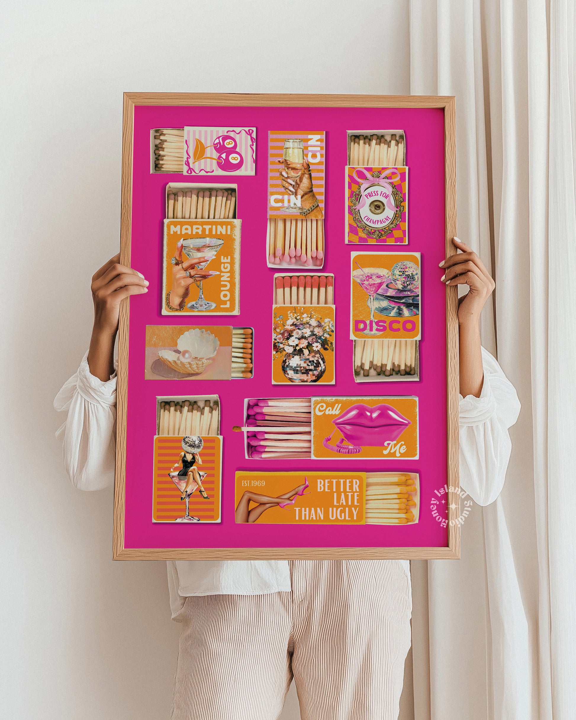 Person holding a framed artwork with matchbox art on a pink background