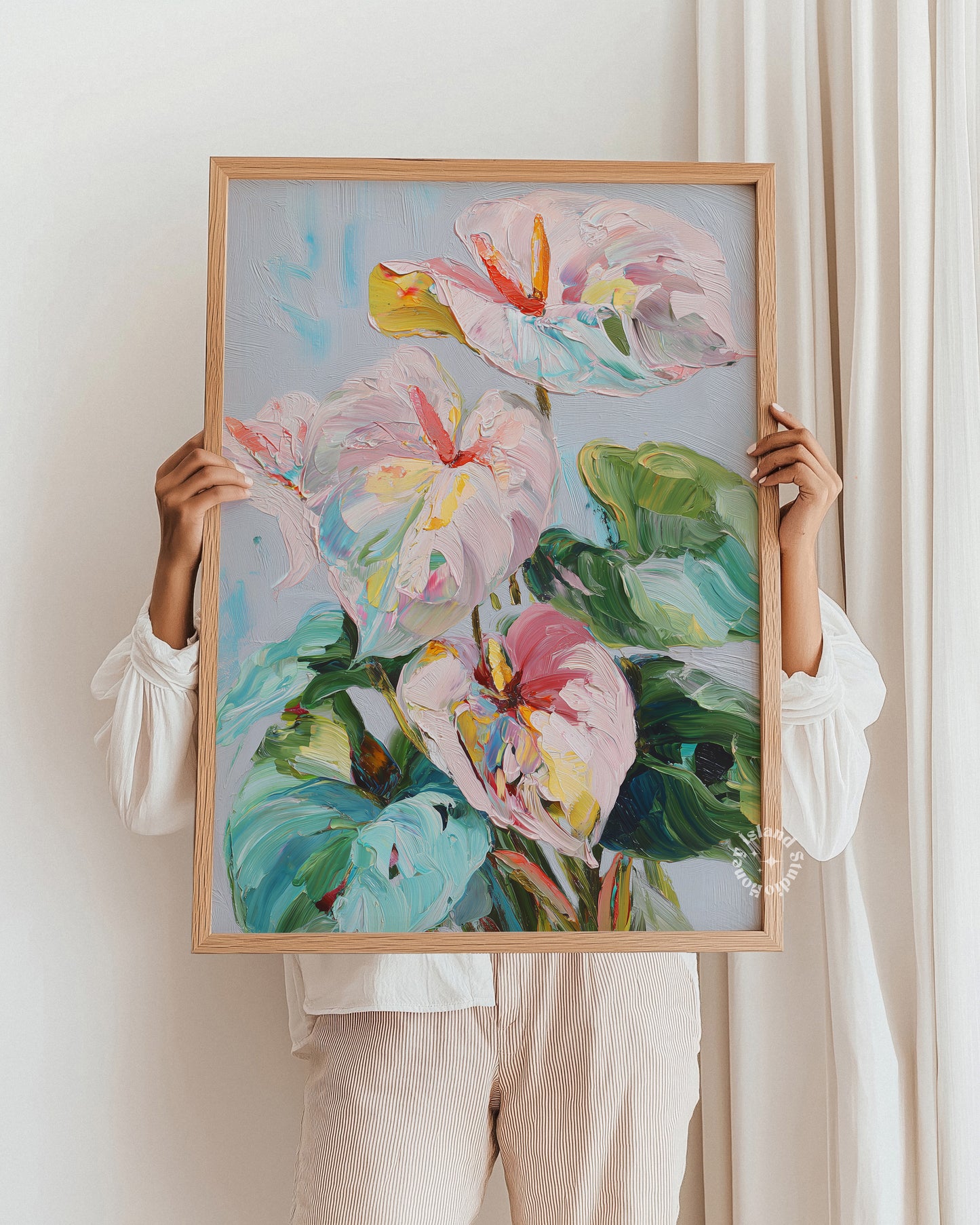 Person holding a framed painting of colorful flowers against a white wall.