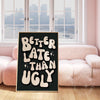 better late than ugly poster print framed next to a pink couch dorm decor