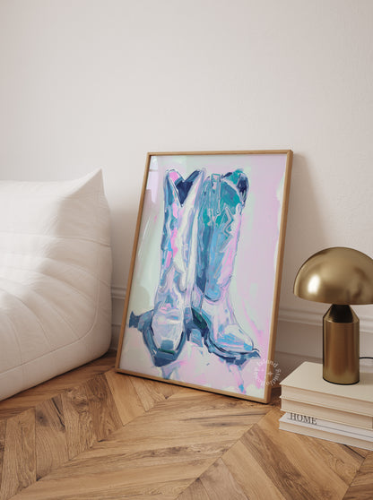 Framed abstract art piece on a side table with a lamp and books in a room.
