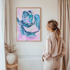 Woman standing in a room looking at an abstract painting on the wall.