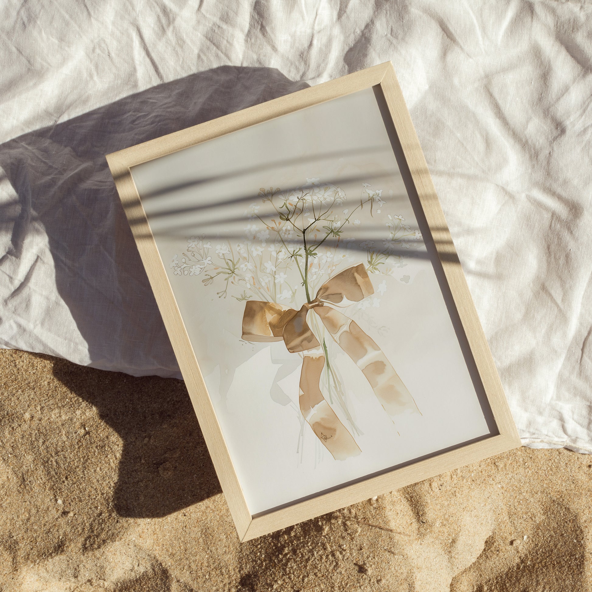 Framed artwork with a plant and bow on a textured surface