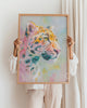 Person holding a colorful painting of a leopard in a wooden frame.