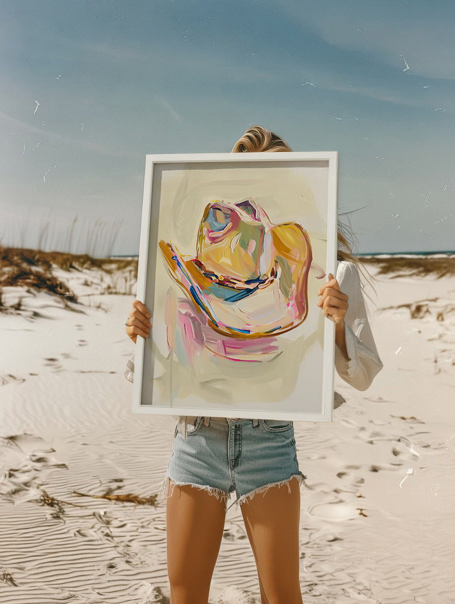 Person holding a framed abstract painting on a beach
