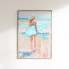 Framed artwork of a woman with a hat and blue bag on a beach.