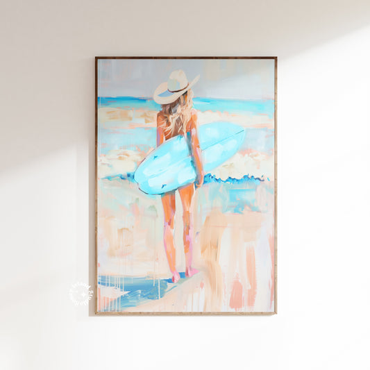 Framed artwork of a woman with a hat and blue bag on a beach.