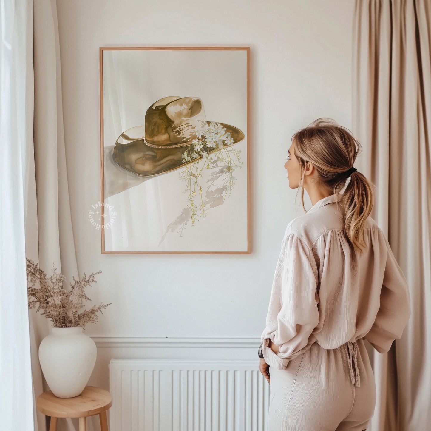 Woman standing in a room with a framed picture of a hat on the wall.
