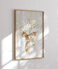 Framed artwork with a bow and flowers on a white wall