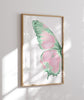 Framed artwork of a pink and green butterfly on a white wall