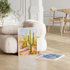 artwork of a desert scene with cacti on a wooden floor in a living room.