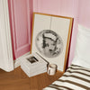 disco ball wall art framed in the floor of a bedroom next to books and mug