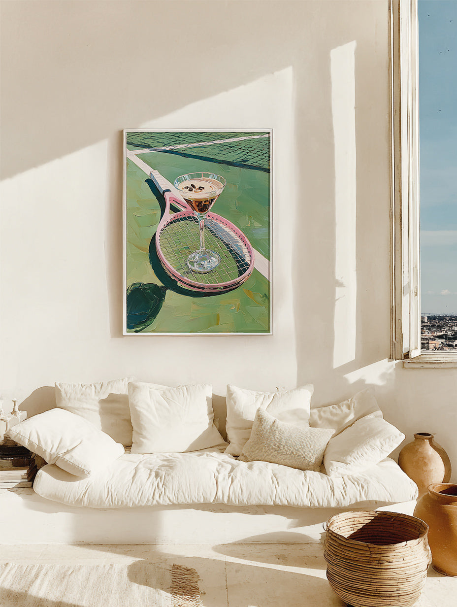 Framed artwork of a cocktail on a pool table in a living room with a white sofa and decorative items.