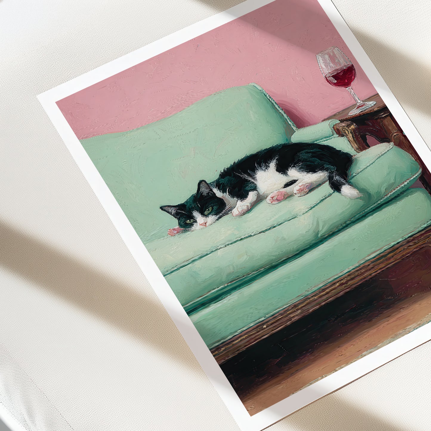 Cat lying on a green couch with a pink wall and wine glass in the background