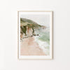 Framed artwork of a coastal landscape with cliffs and beach on a white wall.