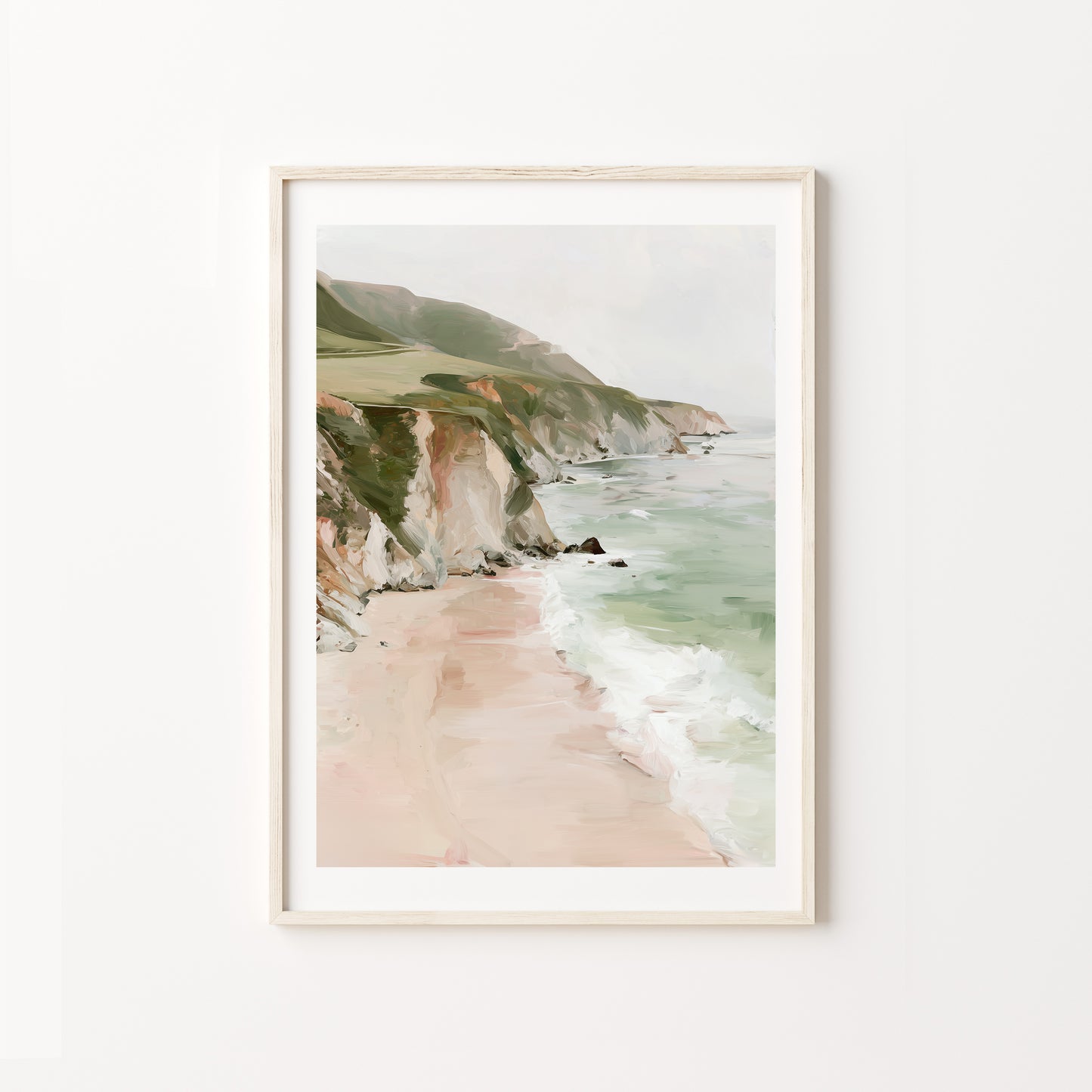 Framed artwork of a coastal landscape with cliffs and beach on a white wall.