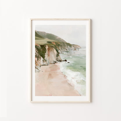 Framed artwork of a coastal landscape with cliffs and beach on a white wall.