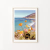 Framed artwork of a coastal scene with flowers on a white wall