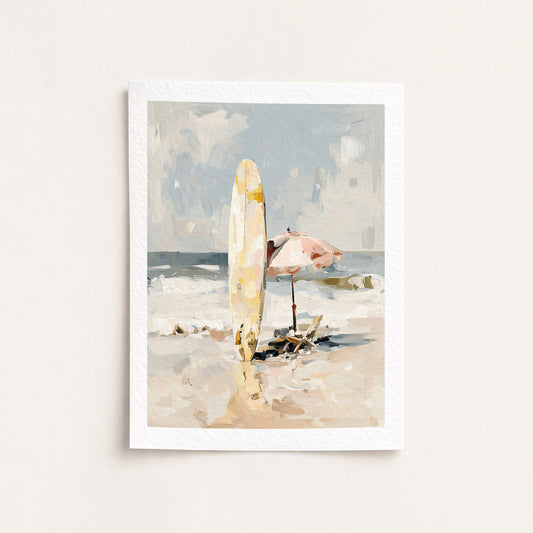 Framed artwork of a beach scene with a surfboard and umbrella on a white wall.