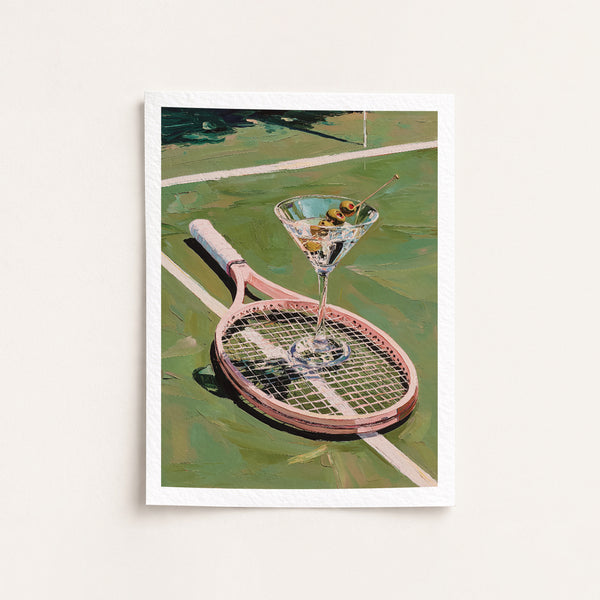 Framed artwork of a martini glass with olives on a tennis racket against a tennis court background.