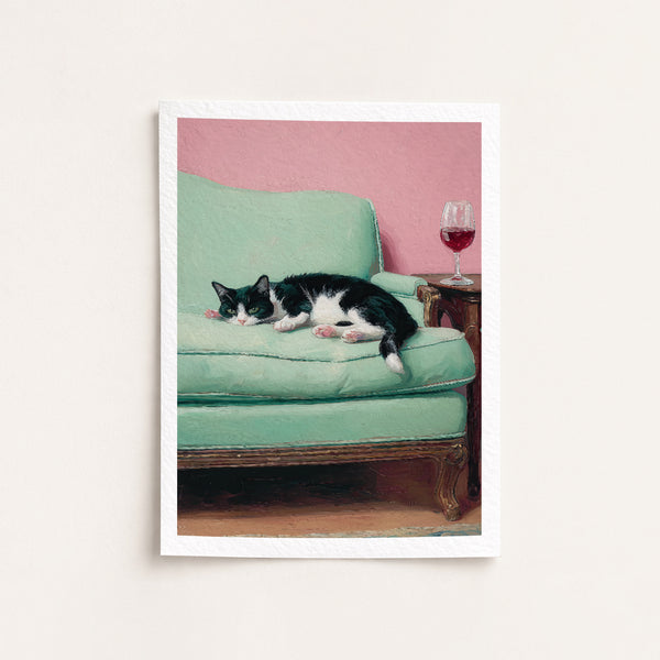 Cat lying on a green couch with a pink wall and wine glass in the background