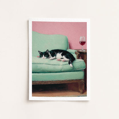 Cat lying on a green couch with a pink wall and wine glass in the background