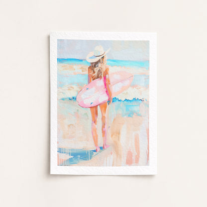 Framed artwork of a woman with a pink surfboard on a beach
