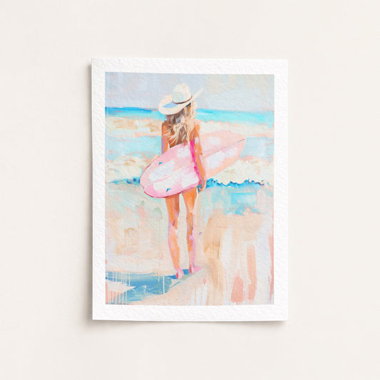 Framed artwork of a woman with a pink surfboard on a beach