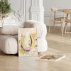 Framed artwork of a colorful horseshoe on a wooden floor with a white armchair and decorative elements.