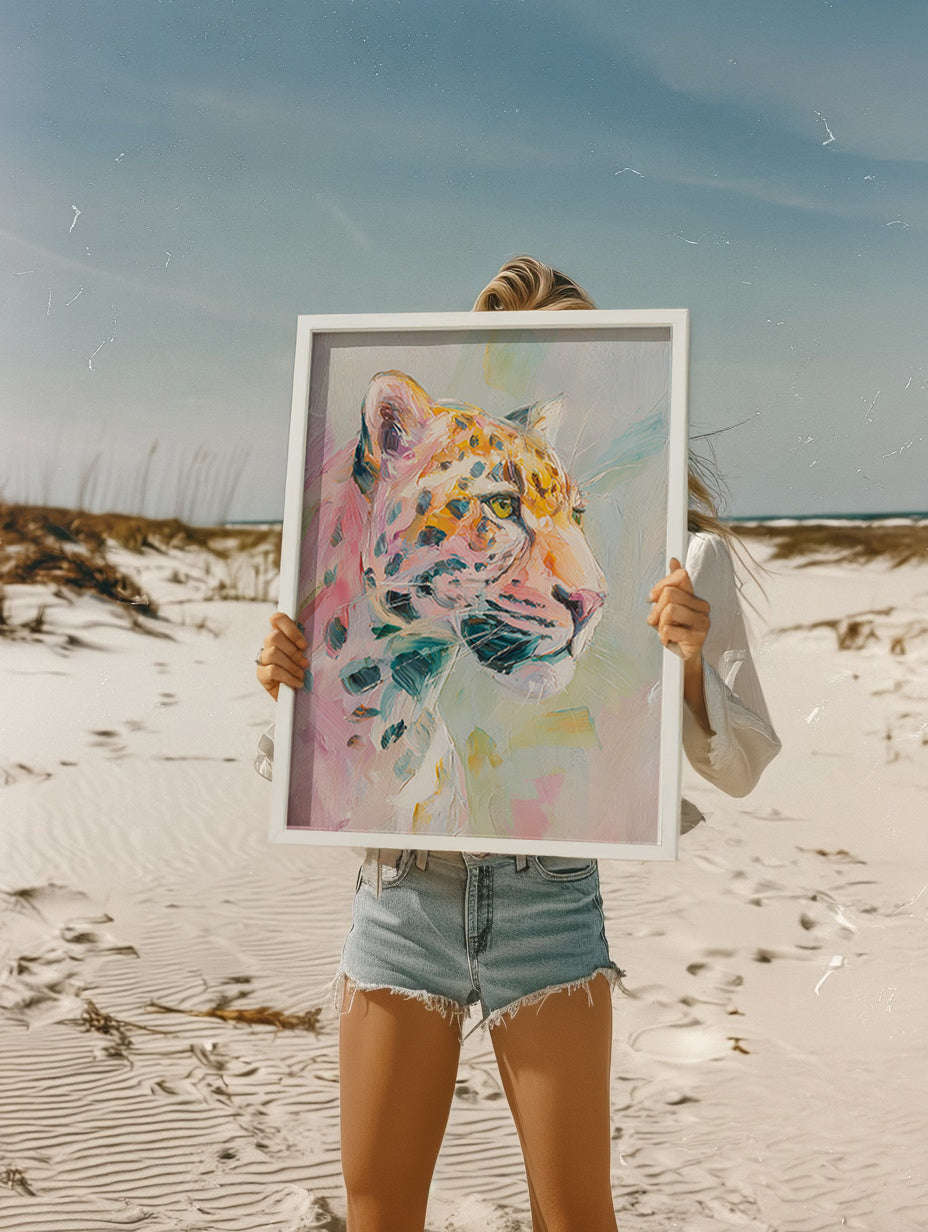 Person holding a framed painting of a colorful leopard on a beach.