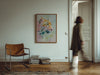 Living room with a brown leather chair, stack of books, and colorful tiger painting on the wall.