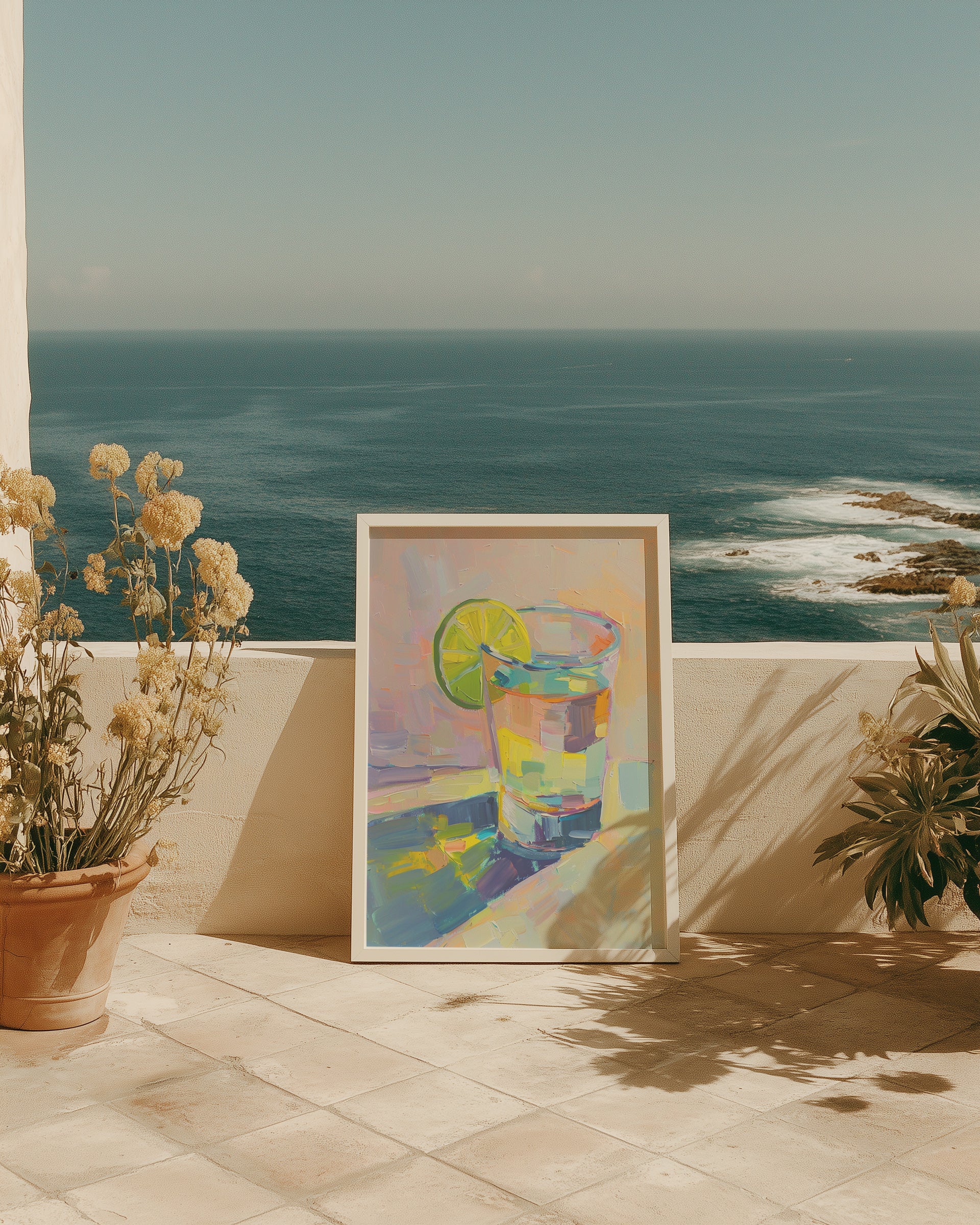 Framed artwork of a colorful drink with a lime on a patio with ocean view