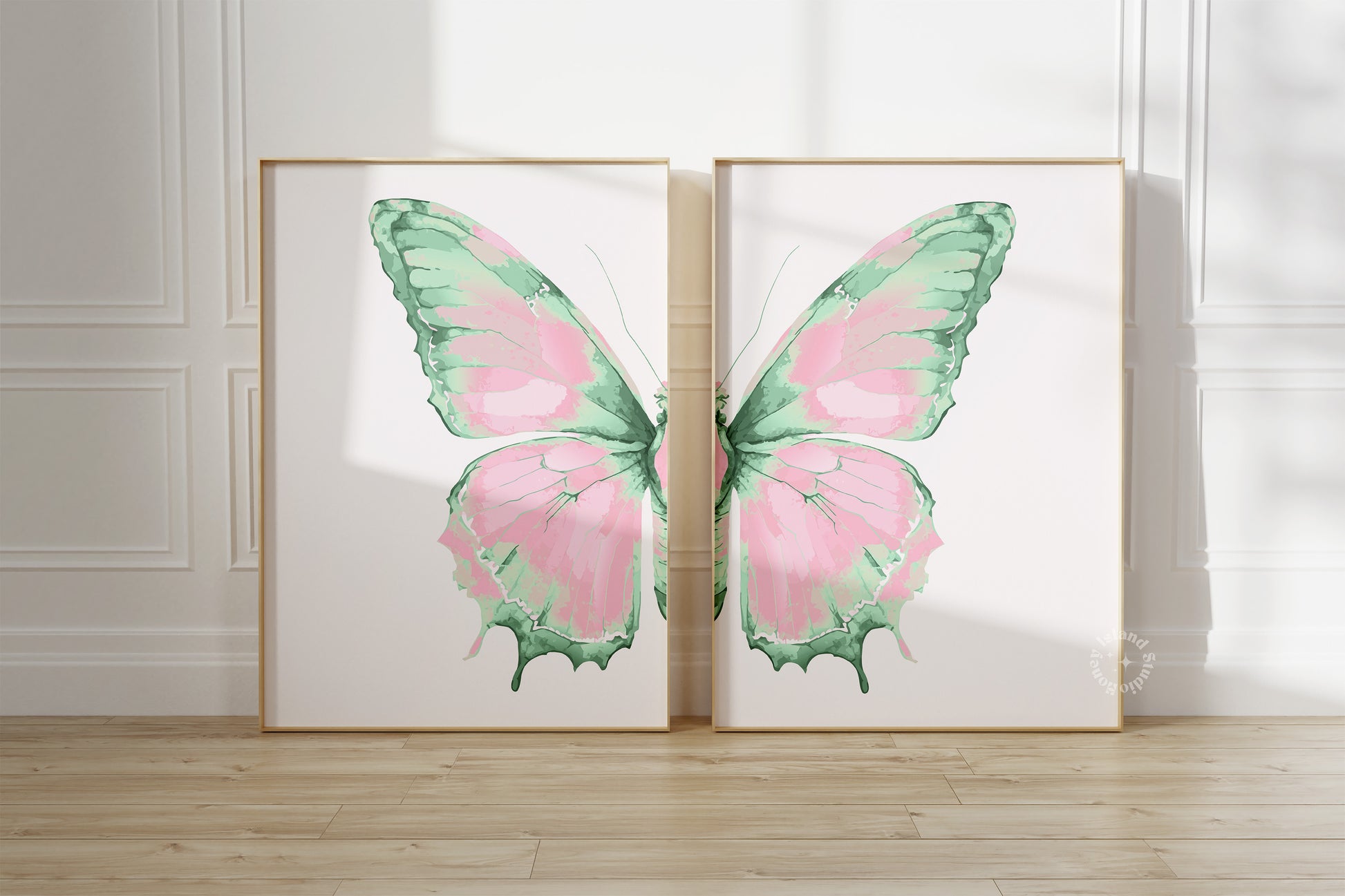 Two framed artworks of pink and green butterflies on a white wall.