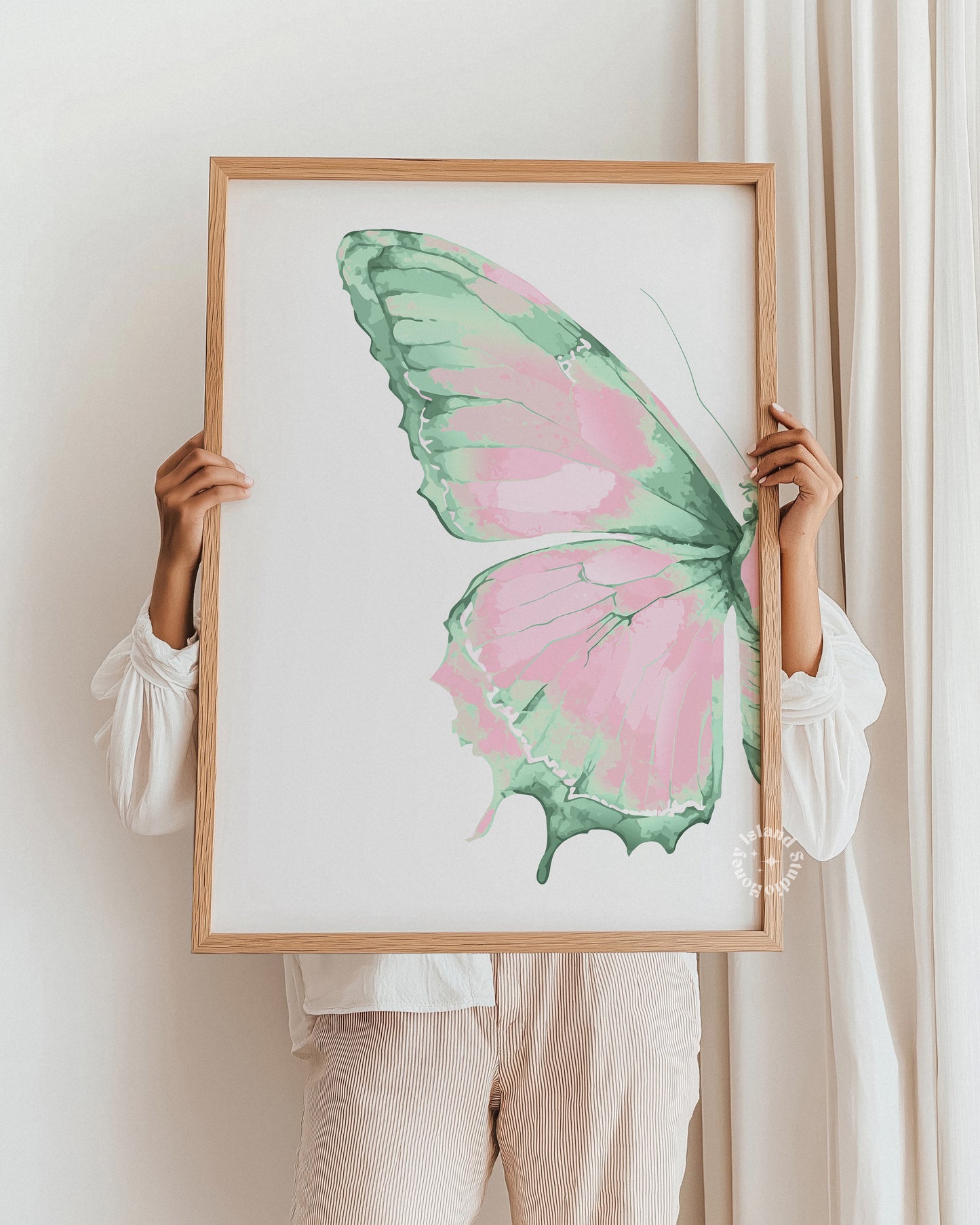 Person holding a framed artwork of a pink and green butterfly