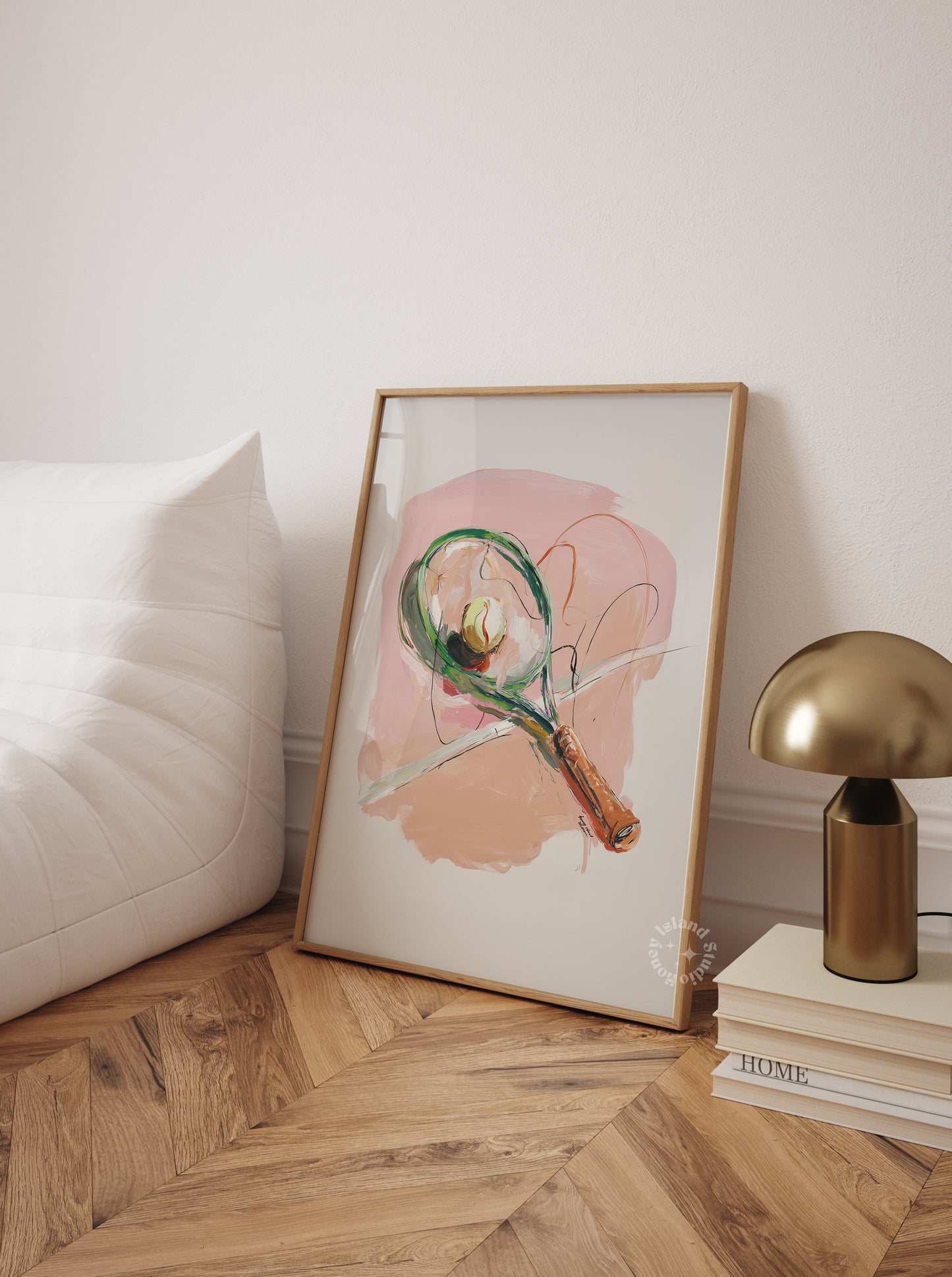 Framed abstract art piece on a wall next to a gold lamp and books.