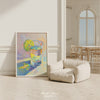 Colorful abstract painting of a tequila glass with a lime on a white wall in a room with a beige armchair.