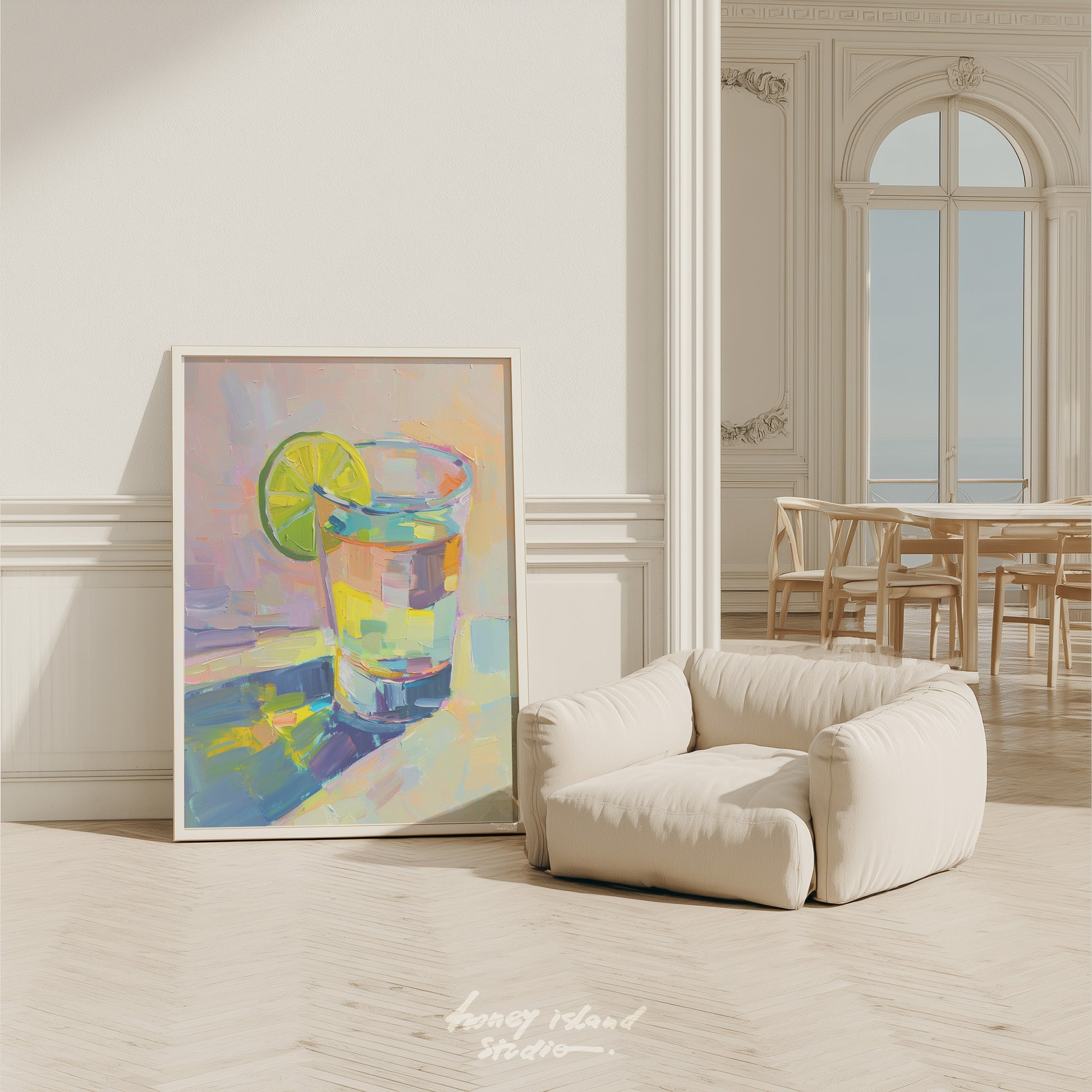 Colorful abstract painting of a tequila glass with a lime on a white wall in a room with a beige armchair.